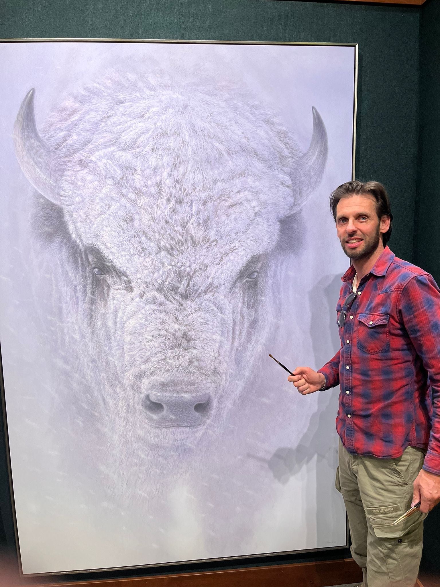 Renso Tamse standing before his Blizzard Chief bison painting, highlighting the artwork and the artist together